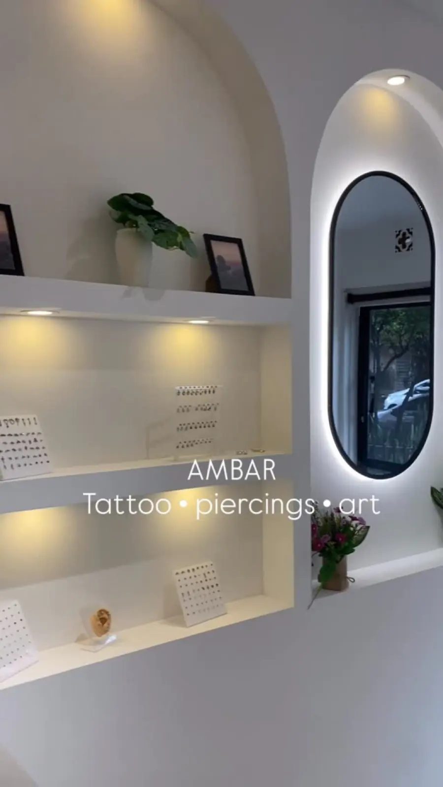 Interior del estudio Ambar con repisas iluminadas, plantas y el logo en la pared