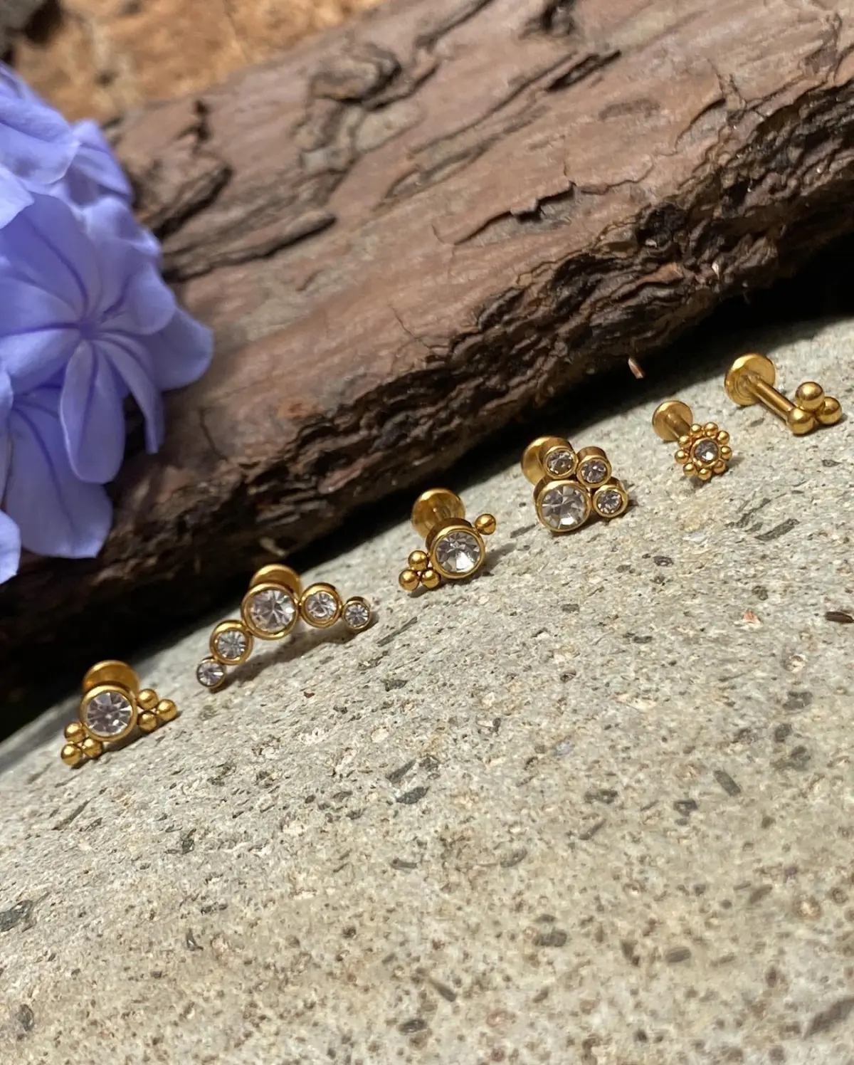Piezas de joyería dorada para piercing sobre piedra y madera