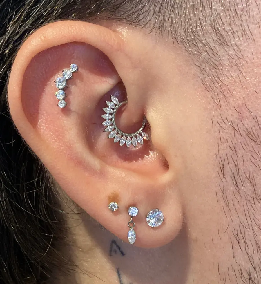 Oreja con varias perforaciones y joyas brillantes