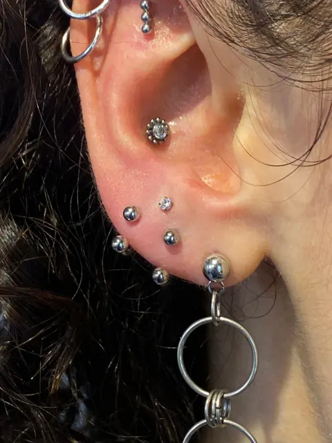 Oreja con perforaciones múltiples y joyas en titanio