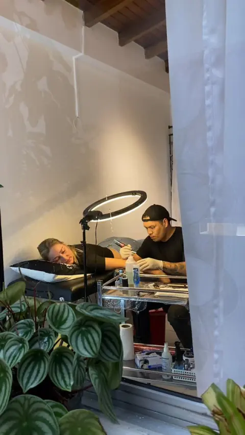 Sesión de tatuaje en el estudio, con luz natural y plantas